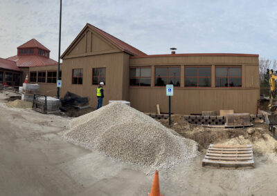 Fenced off exterior construction of the Aurora West Bend facility featuring gravel pile and Beeler employee