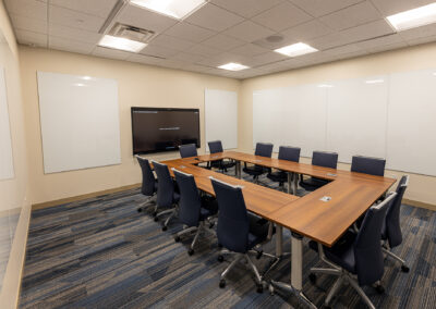 Mid-sided meeting room space at Children's Wisconsin Boardroom Renovation featuring tables, chairs, TV, and white boards