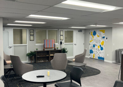 Lounge space featuring chairs, small, round high tables, and high-end Connect Four game from Eastcastle Place senior living facility