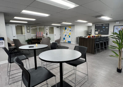 Lounge space featuring chairs, small, round high tables, and TV from Eastcastle Place senior living facility