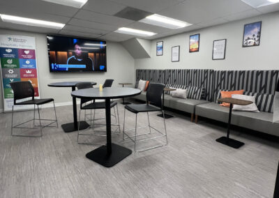 Lounge space featuring chairs, small, round high tables, and TV from Eastcastle Place senior living facility