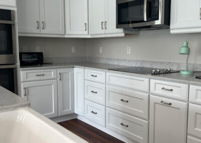 Kitchen space featuring sink, shelving, microwave, and stove top from Eastcastle Place senior living facility