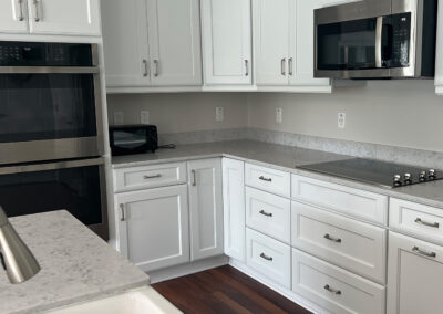 Kitchen space featuring sink, shelving, microwave, oven, and stove top from Eastcastle Place senior living facility