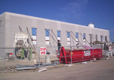 Exterior wall construction of the Henkel Surface Technologies office and laboratory building featuring fencing and garbage trailer