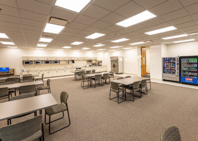 Employee lounge at Uline featuring tables, chairs, vending machines, microwaves, and refrigerator