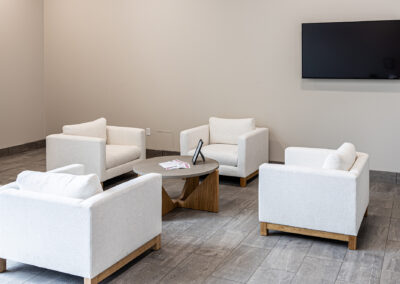 Small meeting space featuring decorative coffee table, white chairs, and TV at Westbrook MTE Tenant Buildout