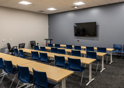 Large meeting room space featuring TV and four rows of tables and chairs