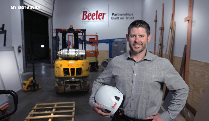 Dave Beeler standing in front of a forklift holding a hard hat.